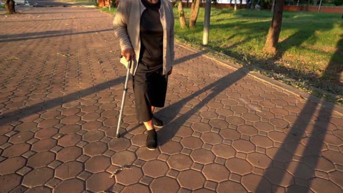 公园里用拐杖走路的高级女性腿的慢速运动