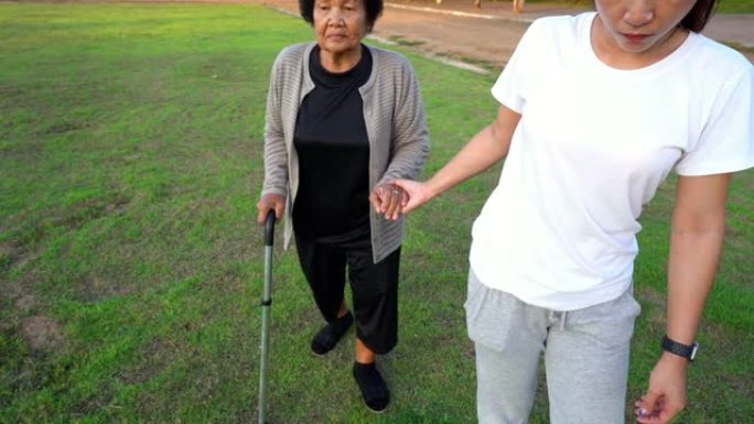 女人的慢动作牵着老妇的手在公园里散步