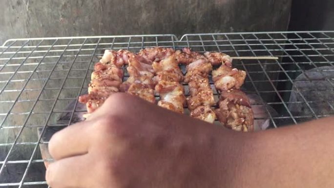 男人的手旋转烧烤块在烤架上烤并抽烟