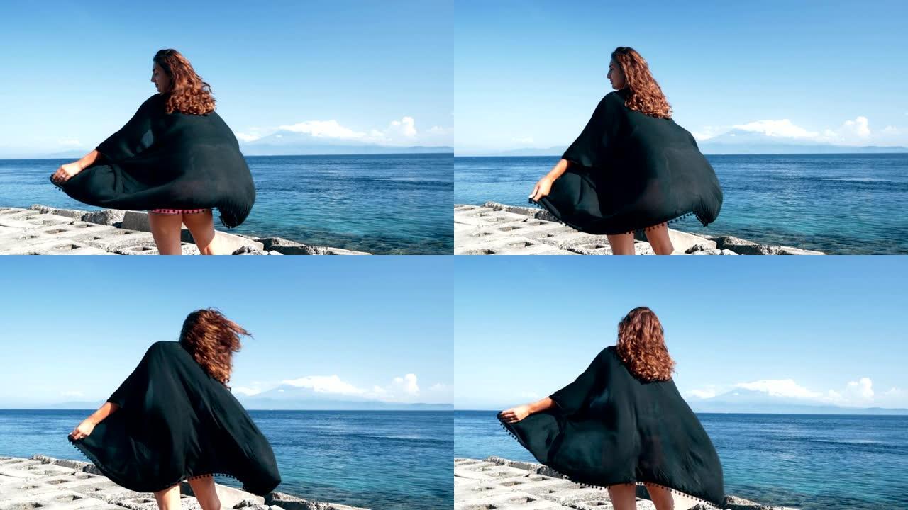 女孩摄影师的侧视图拍摄海洋和山脉的照片。