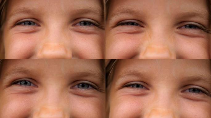 快乐的小女孩眨眨眼，以快乐的目光看着相机的蓝眼睛特写。年轻微笑的孩子用积极的情感看着可爱的脸的肖像。