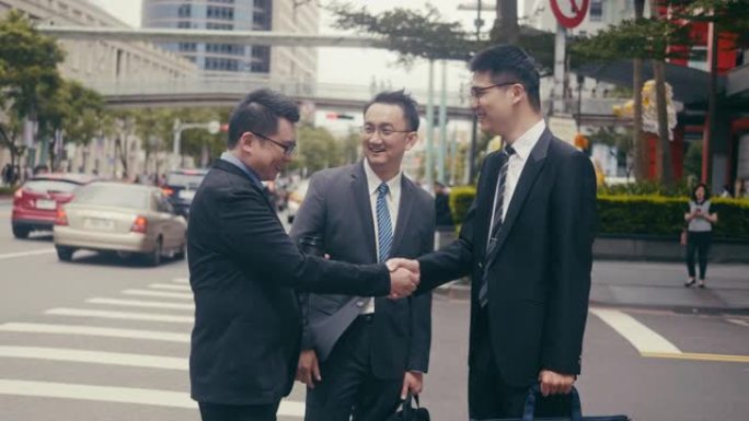 三名亚洲商人在街角见面握手