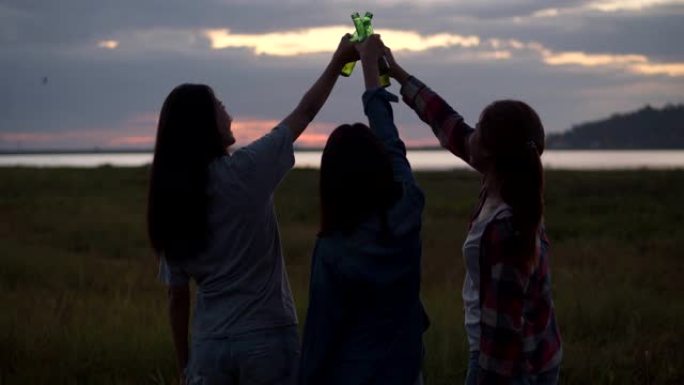 一群年轻的亚洲女性与在大自然中露营的朋友一起庆祝，一起喝啤酒和碰杯。和朋友一起喝啤酒，一边看风景。