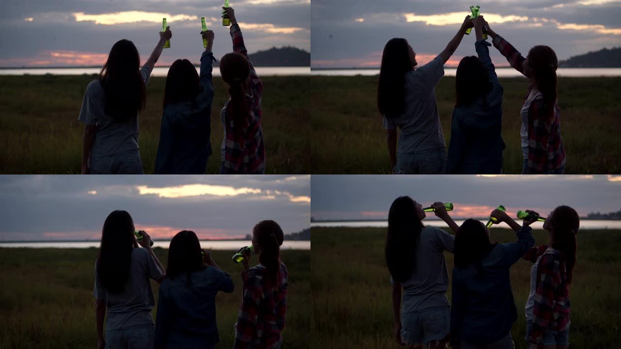 一群年轻的亚洲女性与在大自然中露营的朋友一起庆祝，一起喝啤酒和碰杯。和朋友一起喝啤酒，一边看风景。