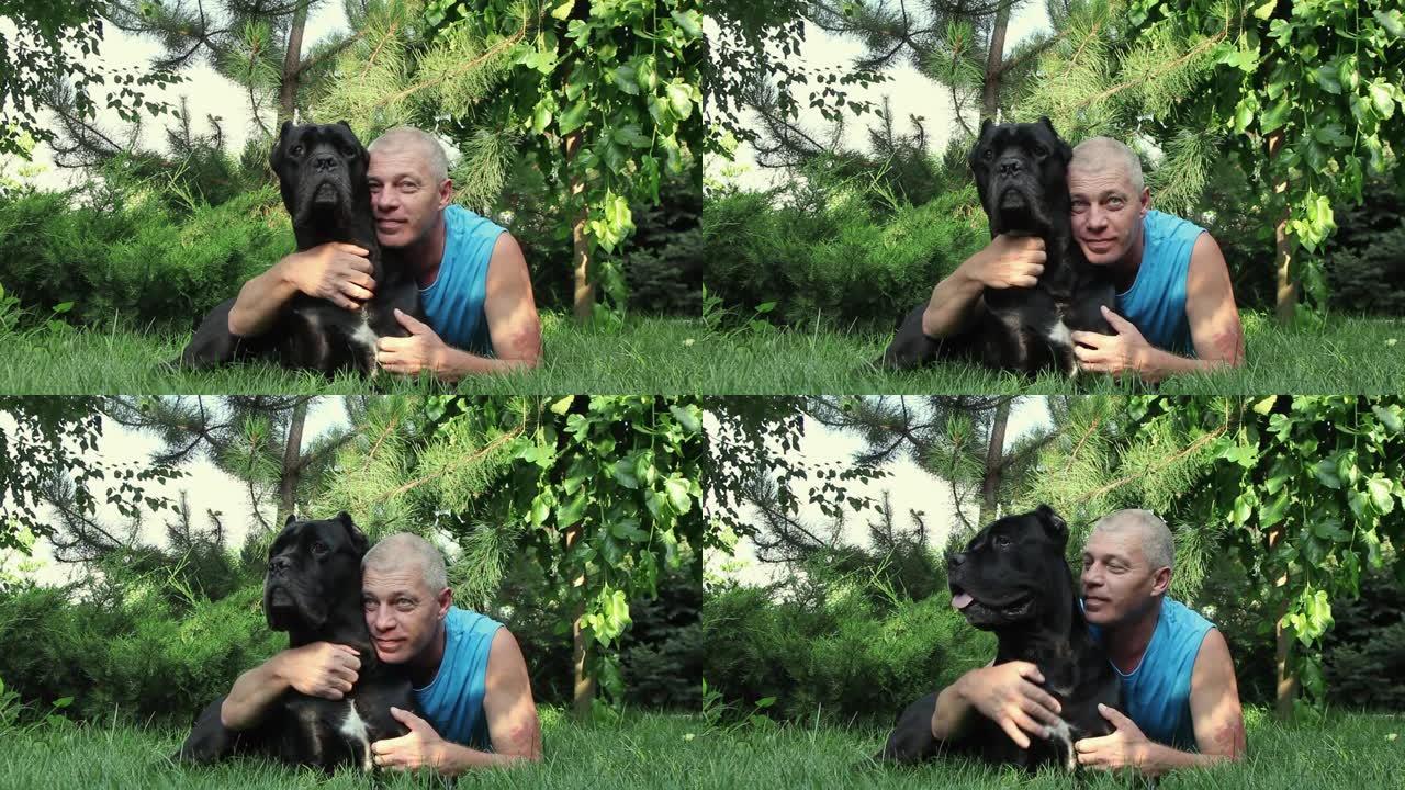 年轻人带着他心爱的黑甘蔗科索狗躺在枞树下的绿草上