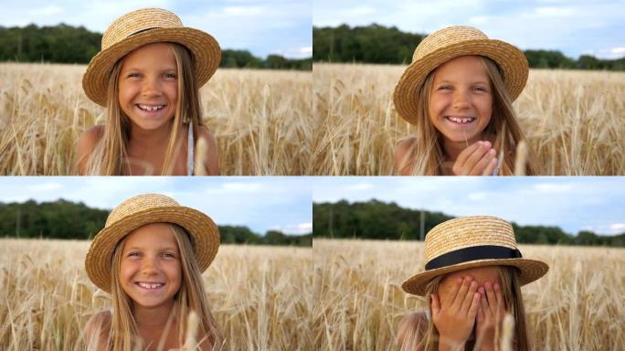 戴着草帽的美丽小女孩的肖像看着相机，笑着用手遮住了脸。快乐的小孩坐在麦田的背景下，带着快乐的微笑。特