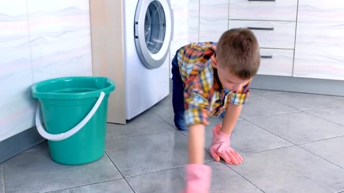 戴着橡胶手套的男孩在厨房洗地板。孩子的家庭职责。