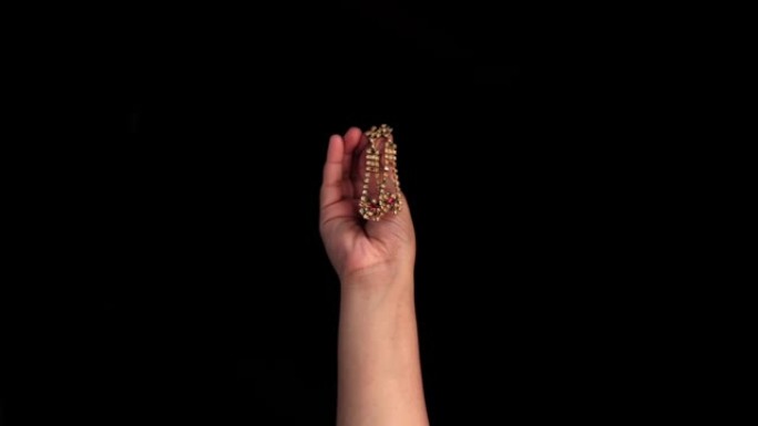 一只女性的手出现在黑色背景上，显示出金色的印度风格耳环。