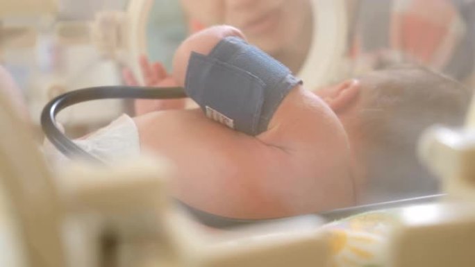 医生们正在对一名新生婴儿进行治疗。儿科医生正在动新生婴儿的手。分娩之家和儿童健康概念。幼儿保育箱，拯