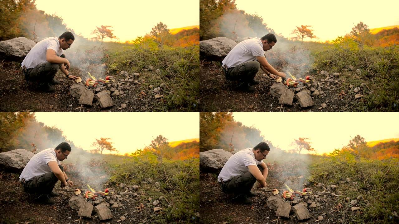 森林里的香肠烧烤。男人在大自然中烤香肠
