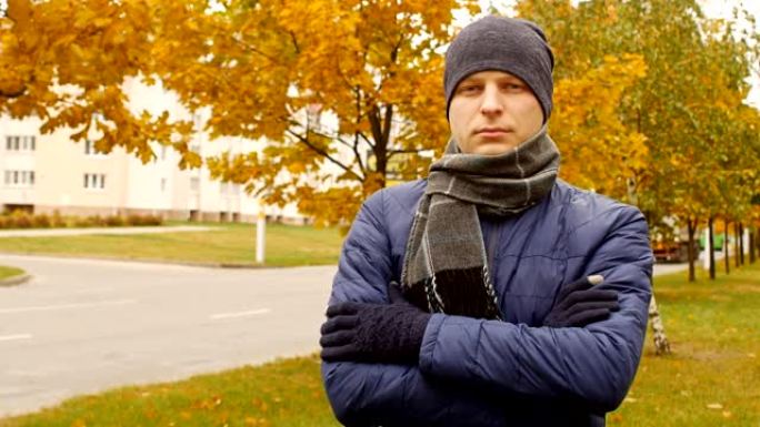 在城市的秋天或秋天外面，戴着围巾和帽子的男人的肖像