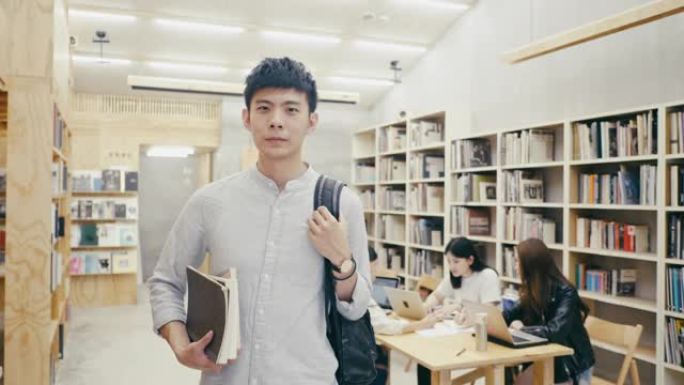 一名年轻的亚洲男学生站在图书馆的肖像
