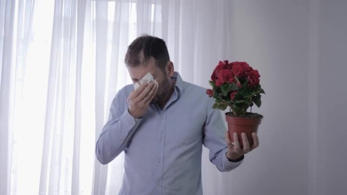 过敏男性，男性手拿花患有呼吸系统疾病由于对花粉敏感而打喷嚏和擦脸