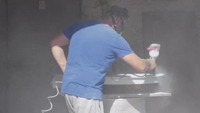 车库里戴防毒面具的成熟男人喷漆白色木桌