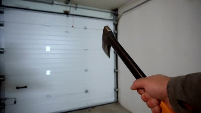 从摄像机的侧面看，手里拿着斧头，在车库里