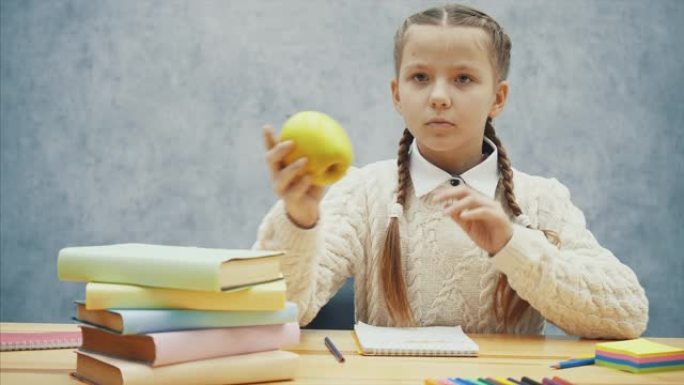 女学生停止写作，闻到美味的黄苹果。