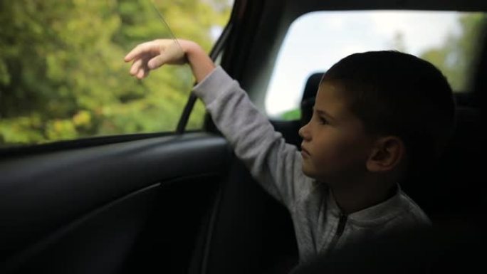 小男孩在汽车背面开车，放松和享受公路旅行