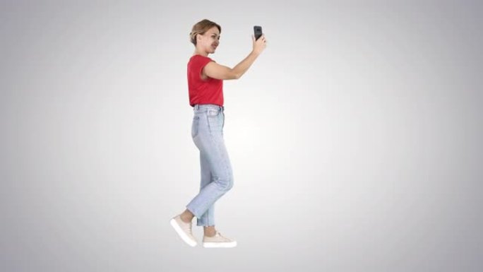 年轻可爱的女士正在渐变背景上的手机视频博客上进行视频通话