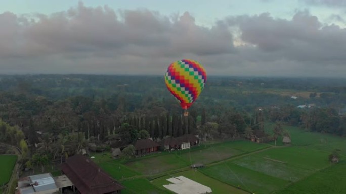 空中拍摄的热气球正在大绿稻田上空飞行。前往巴厘岛的概念