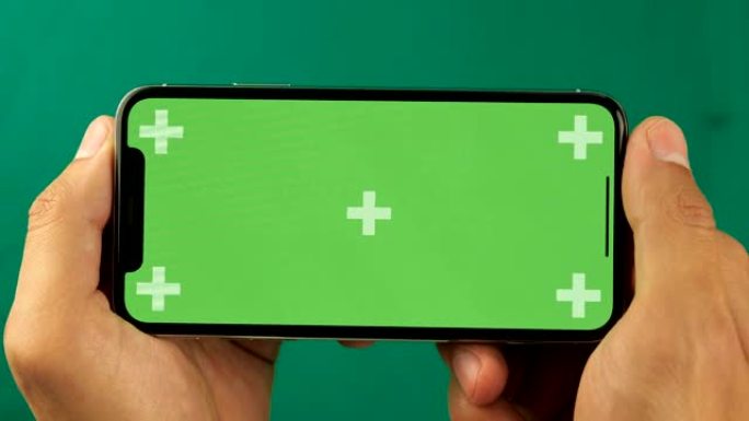 Close up man手持水平位置的绿色屏幕色度键智能手机，并翻阅照片。幻灯片的好镜头