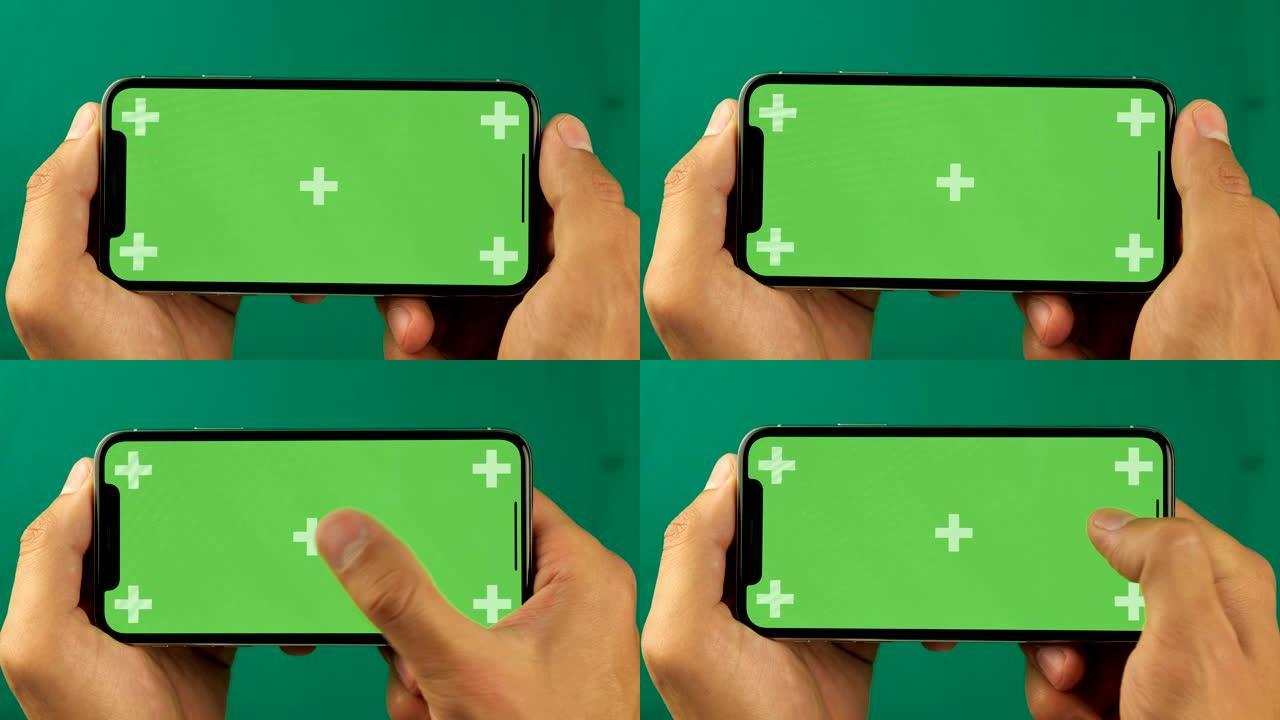 Close up man手持水平位置的绿色屏幕色度键智能手机，并翻阅照片。幻灯片的好镜头