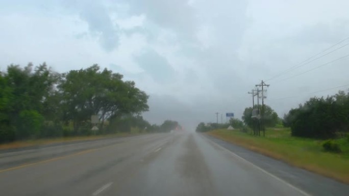 驾驶员POV开着挡风玻璃刮水器，在德克萨斯州的一条柏油路上行驶