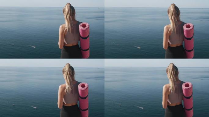 运动员女孩手里拿着手机的背面视图，背景是海洋