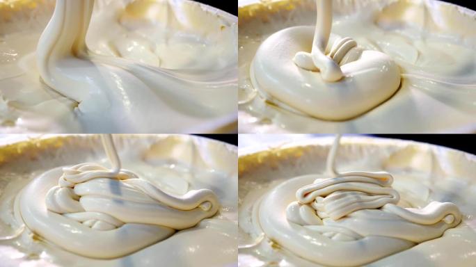 令人印象深刻的浓稠酸奶油混合在一起，被一个大塑料勺拿走。它以螺旋的方式像一条狭窄的小溪一样向下运走