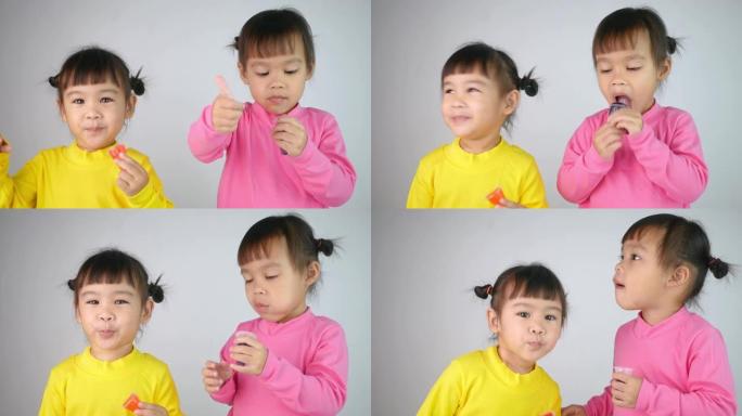 一个快乐微笑的兄弟女孩的肖像，喜欢吃白色背景上孤立的明胶甜点。
