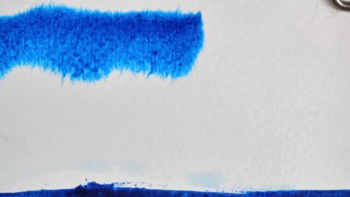 蓝色水彩在白色潮湿的表面上流动和扩散