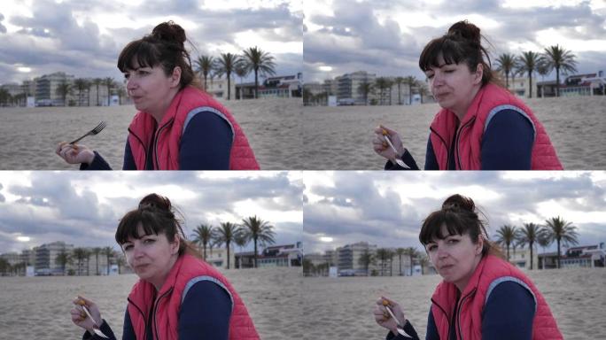 女人坐在海边的海滩上吃西瓜，玩得开心，旅行概念