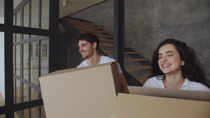 微笑的男人和女人以慢动作将纸盒放在地板上。