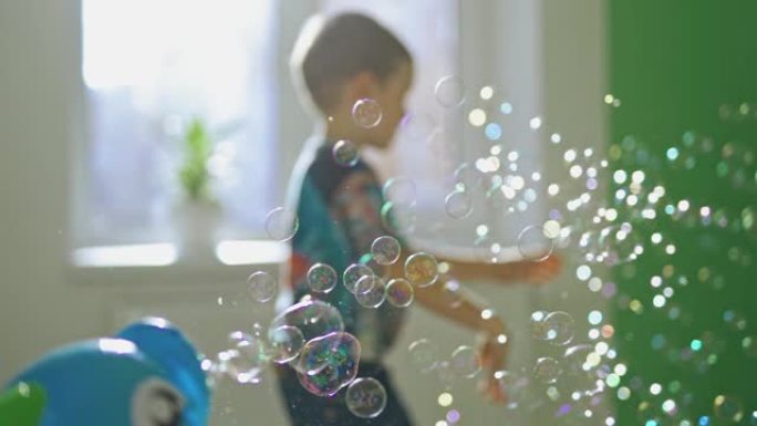 许多水泡在房间里飞舞在模糊的背景和一个小男孩。