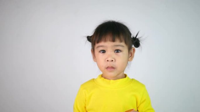 一个快乐微笑的亚洲儿童女孩的肖像，喜欢吃孤立在白色背景上的果冻。