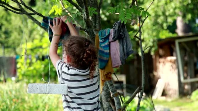 小女孩把洗过的衣服挂在后院的树枝上时感到害怕