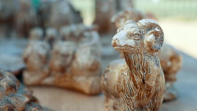 一只带有弯曲角的民间传说山羊的惊人景色被放置在其他纪念品中，展示了由石头制成的人和动物