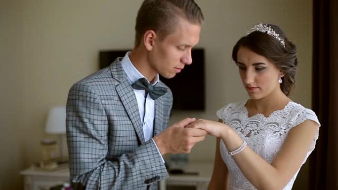 婚礼当天，新郎在酒店房间帮助戴上新娘手镯