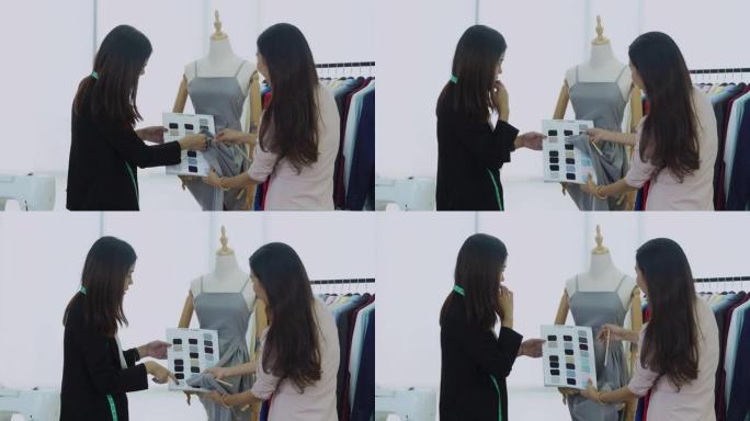 两名亚洲设计师选色裁缝服装以满足顾客需求