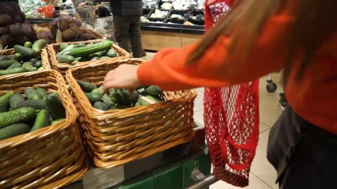 年轻女子在网状有机购物袋中采摘蔬菜和水果，零浪费