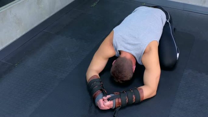 运动员在健身房使用教练进行肌筋膜伸展后，在垫子上休息。