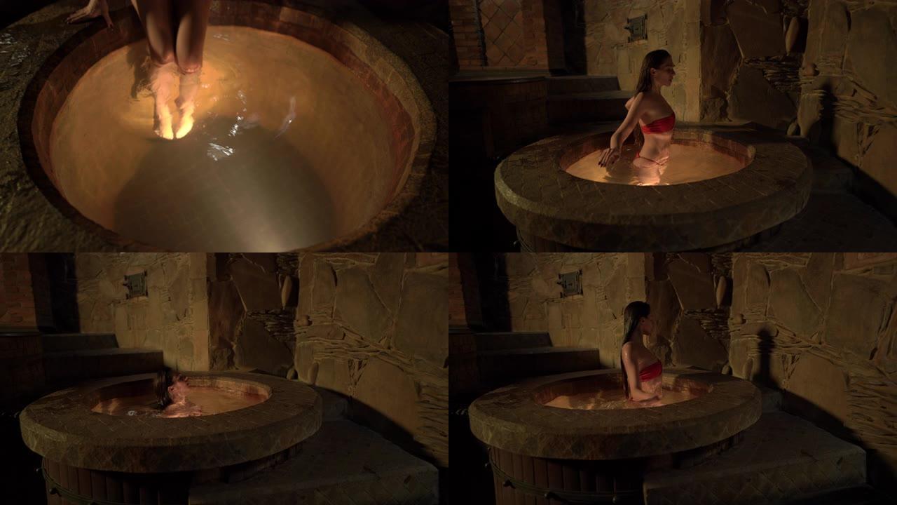 一个美丽的年轻女子用地下天然温泉水跳入浴缸的特写镜头。水疗和健康。