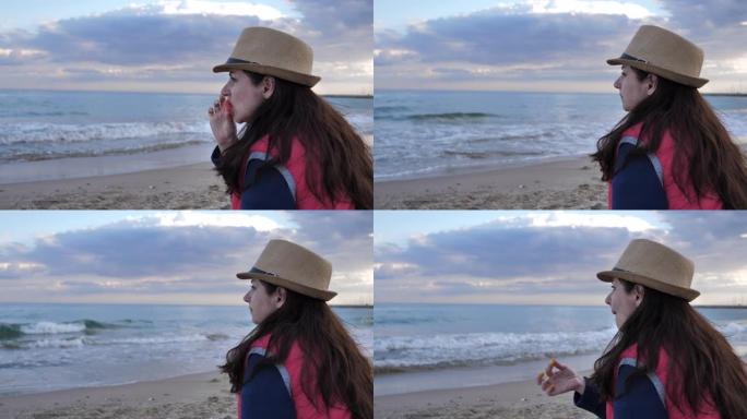女人坐在海边的海滩上吃西瓜，玩得开心，旅行概念