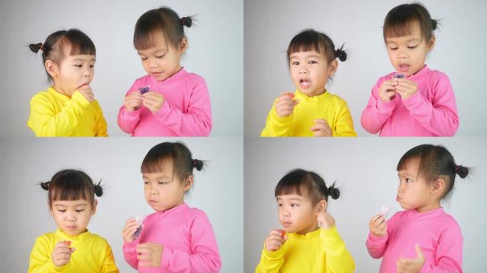 一个快乐微笑的兄弟女孩的肖像，喜欢吃白色背景上孤立的明胶甜点。
