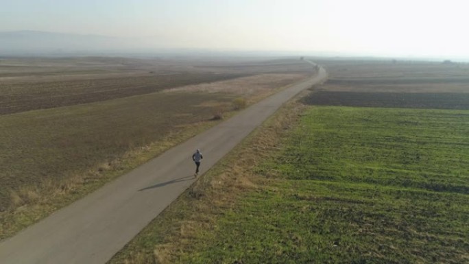 在乡村道路上慢跑的男子的无人机视图