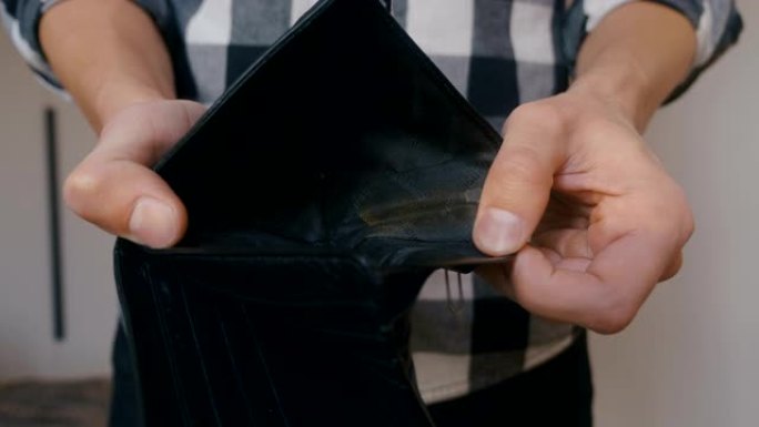 男人手里拿着皮钱包的特写镜头，没有钱。贫困的概念