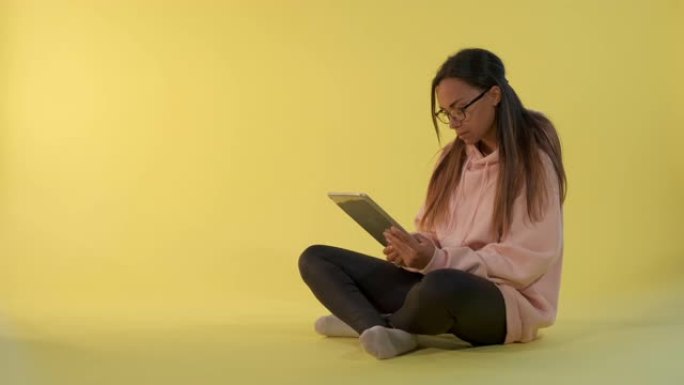 迷人的混血女孩在平板电脑上阅读一些东西，然后看着眼镜对着相机