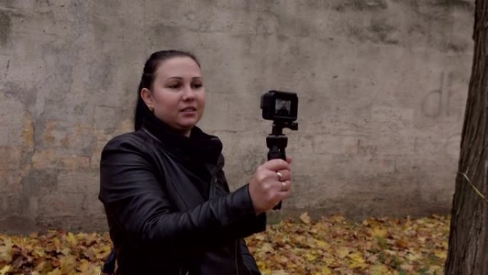 女人在秋季公园的摄录机上拍摄自己