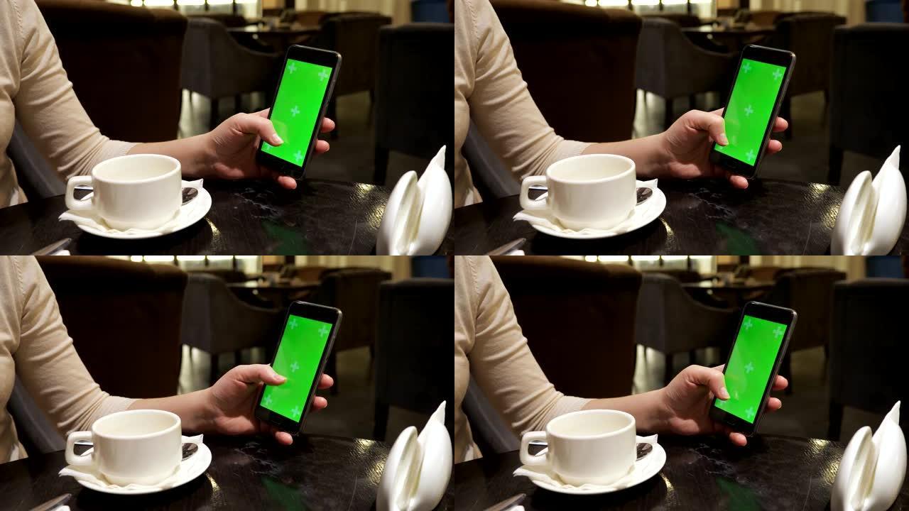 女孩的手在咖啡馆里用绿屏翻阅感应电话