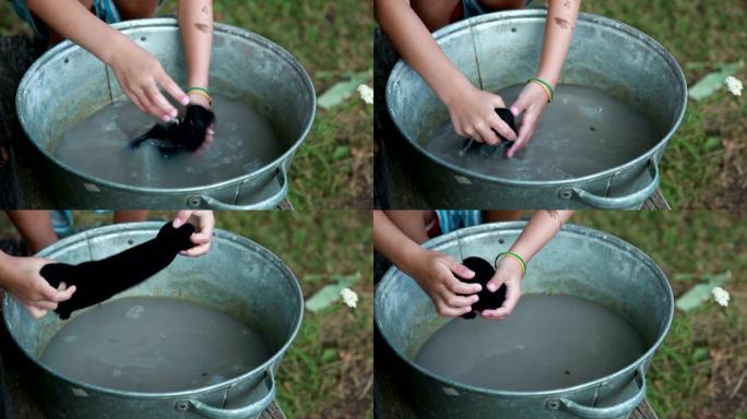 一个小女孩在金属盆里洗脏袜子的手特写