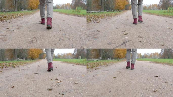 阴天女性腿在公园慢动作后视的沙质小径上行走
